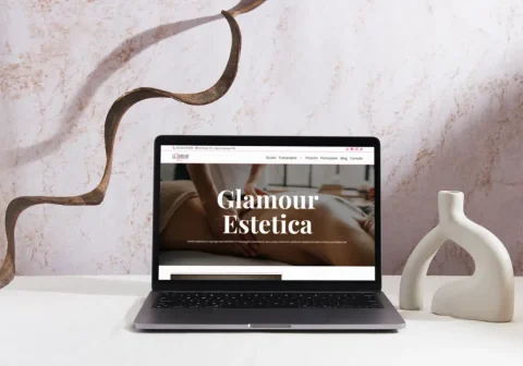 Laptop su un tavolo con un vaso dove si vede la prima pagina del sito Glamour Estetica