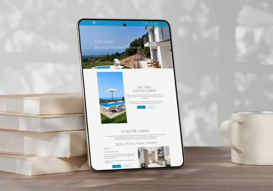 Tablet su un tavolo appoggiato a dei libri che mostra il sito di The View Lakegarda